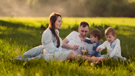 Children-feed-mom-on-a-picnic-ice-cream-family-lunch-outdoors-in-the-field-in-nature.